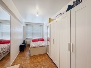 Chambre moderne et chaleureuse avec lit floral grand miroir parquet en bois et luminosité naturelle