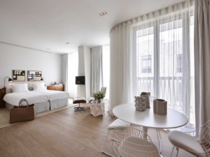 Chambre moderne minimaliste lumineuse avec grand lit coin repas œuvres dart et vue sur balcon