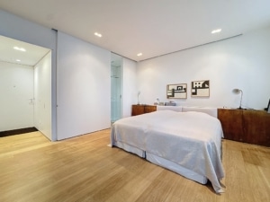 Chambre moderne et zen avec lit queen mobilier en bois œuvres abstraites cloison en verre ambiance apaisante