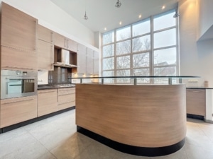 Cuisine moderne lumineuse avec îlot en bois courbé grandes fenêtres et rangements intégrés
