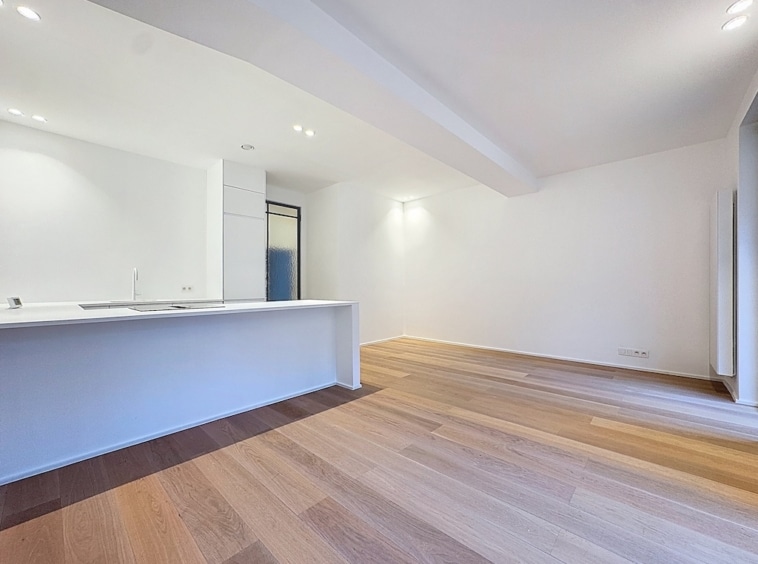 Cuisine moderne lumineuse avec îlot blanc, sol en bois clair et ambiance épurée.