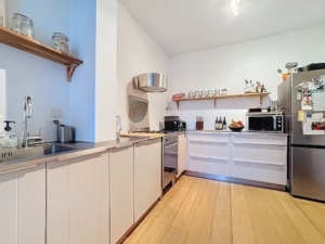 Cuisine moderne lumineuse avec îlot blanc plan quartz électroménagers élégants et sol en bois clair