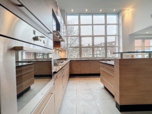 Cuisine contemporaine lumineuse avec îlot central meubles en bois grande baie vitrée électroménagers en inox