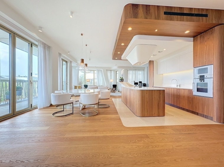 Cuisine moderne lumineuse avec îlot en bois, vue extérieure et espace convivial.