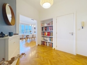 Entrée lumineuse avec bibliothèque parquet en chevrons miroir rond et espace accueillant