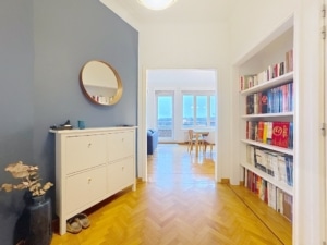 Hall moderne lumineuse avec mur bleu miroir rond bibliothèque et parquet clair vue sur espace convivial