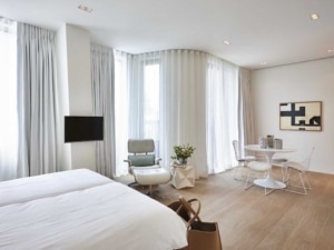 Chambre dhôtel moderne lumineuse épurée avec lits confortables coin lecture verte et espace repas élégant
