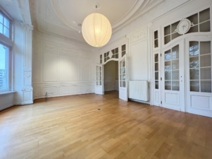 Intérieur lumineux avec moulures classiques sol en bois grande fenêtre et éclairage moderne