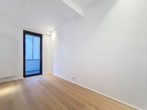 Intérieur minimaliste lumineux avec murs blancs sol en bois clair et grande fenêtre