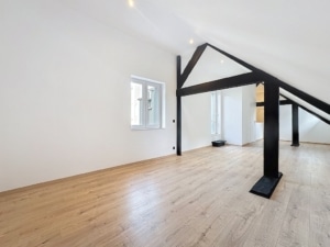 Espace minimaliste lumineux avec murs blancs plafond en pente noir et sol en bois clair