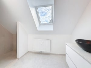 Intérieur minimaliste lumineux avec plafond incliné radiateur blanc discret et console élégante avec bol noir