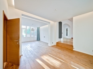 Intérieur contemporain lumineux avec escalier, arches, murs blancs, sols en bois, ambiance minimaliste.