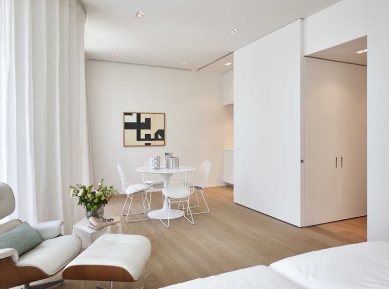 Intérieur minimaliste moderne avec mobilier blanc, art géométrique et ambiance lumineuse naturelle.