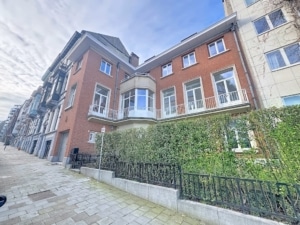 Maison résidentielle mixant architecture classique en briques rouges et design moderne, quartier calme.