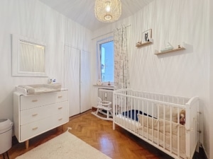 Nursery moderne et apaisante avec mobilier blanc parquet chaleureux lumière douce et ambiance sereine