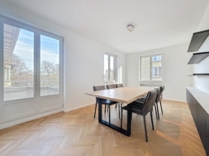 Salle à manger moderne lumineuse avec table en bois chaises noires et grandes fenêtres