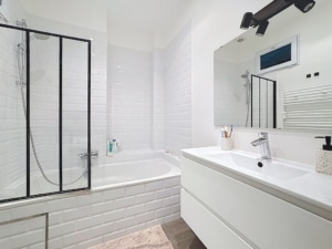 Salle de bain moderne blanche avec baignoire encastrée douche en verre et meuble épuré