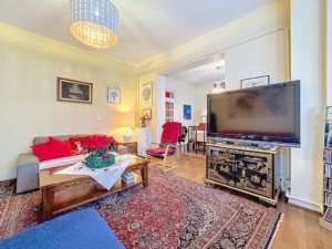 Salon chaleureux avec canapé gris coussins rouges tapis coloré et espace repas convivial