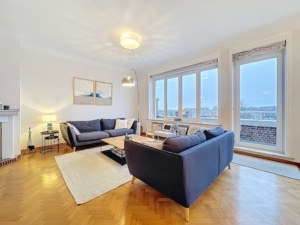 Salon moderne avec canapés gris lumière naturelle vue urbaine et déco chaleureuse