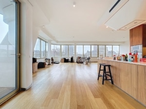 Appartement moderne avec cuisine ouverte, vue urbaine panoramique et intérieur lumineux en bois naturel.