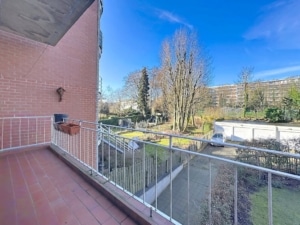Balcon résidentiel avec vue sur jardin verdoyant et ciel bleu ambiance paisible et chaleureuse