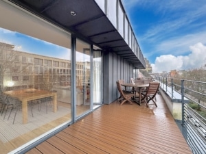 Balcon contemporain avec mobilier en bois, vue urbaine et espace repas lumineux.
