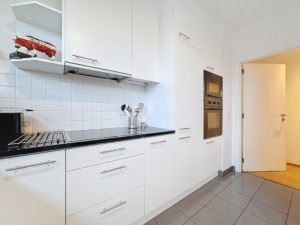 Cuisine moderne élégante avec plans en granite noir, armoires blanches et éclairage naturel.