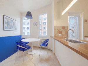 Cuisine moderne lumineuse avec coin repas coloré et espace convivial éclairée par grande fenêtre