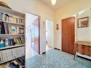 Entrée accueillante avec bibliothèque, portes variées et décor chaleureux en bois.