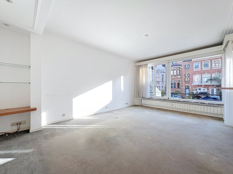 Intérieur lumineux et minimaliste avec grandes fenêtres et vue urbaine moderne.