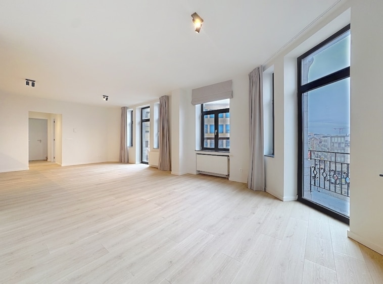 Intérieur contemporain lumineux avec grandes fenêtres, sol en bois clair, espace ouvert et minimaliste.