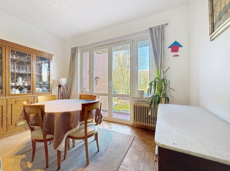 Salle à manger chaleureuse avec vue végétale, mobilier en bois et décoration élégante.