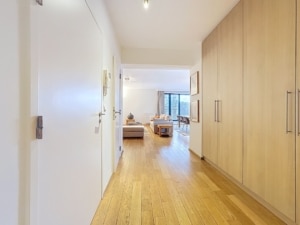 Couloir lumineux avec rangements modernes menant à un salon convivial et lumineux