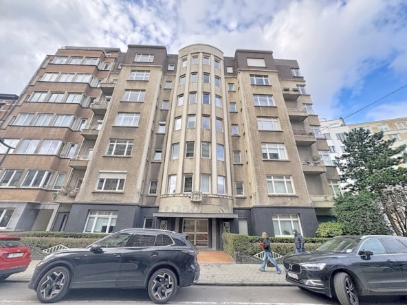 Immeuble résidentiel art déco avec tour arrondie façade en brique fenêtres élégantes rue animée