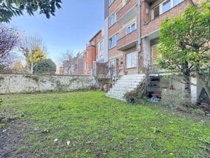 Jardin verdoyant avec terrasse et vue urbaine jouant sur nature et architecture moderne