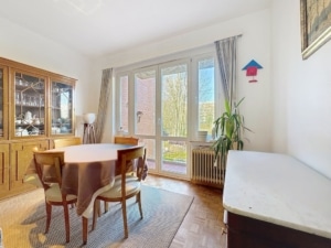 Salle à manger lumineuse avec table en bois, plantes vertes et décoration naturelle accueillante.