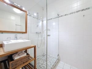 Salle de bain moderne avec douche en verre lavabo en bois grand miroir et décoration épurée