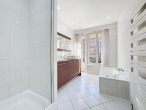 Salle de bain lumineuse moderne avec baignoire douche en verre et mobilier en bois élégant