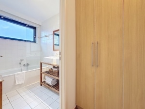 Salle de bain moderne lumineuse avec baignoire rangements en bois et miroir élégant