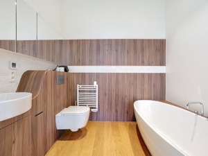 Salle de bain moderne en bois clair avec baignoire lavabo épuré toilette suspendue et lumière naturelle