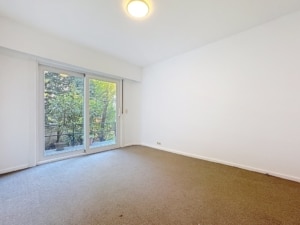 Espace lumineux avec grande porte fenêtre donnant sur un jardin verdoyant idéal pour tous usages