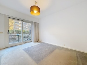 Salon lumineux minimaliste avec vue sur jardin grande baie vitrée et éclairage chaleureux