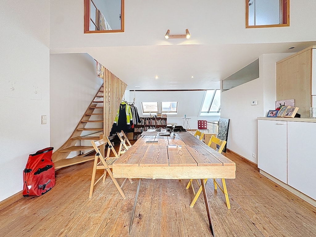 Espace de vie lumineux à Paris avec coin repas en bois, salon cosy et escalier en bois