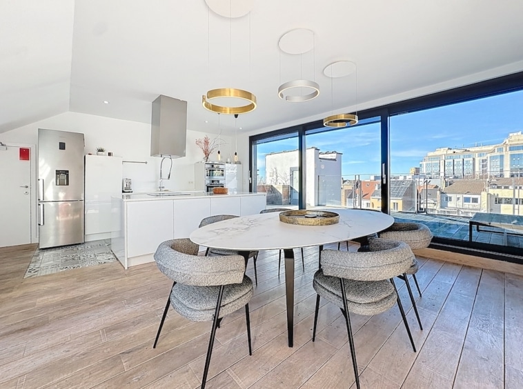 Cuisine contemporaine lumineuse avec vue, table ronde, chaises gris, appareils en inox, style élégant.