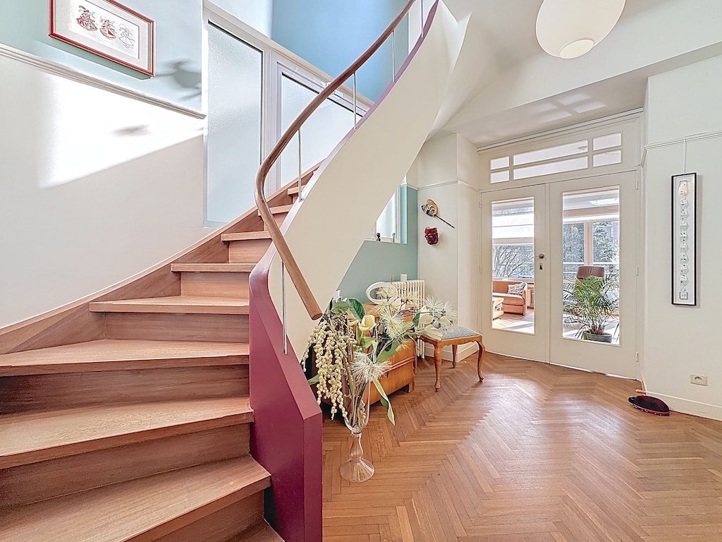 Escalier en spirale en bois naturel dans intérieur lumineux avec jardin à Woluwe, style moderne et cosy.