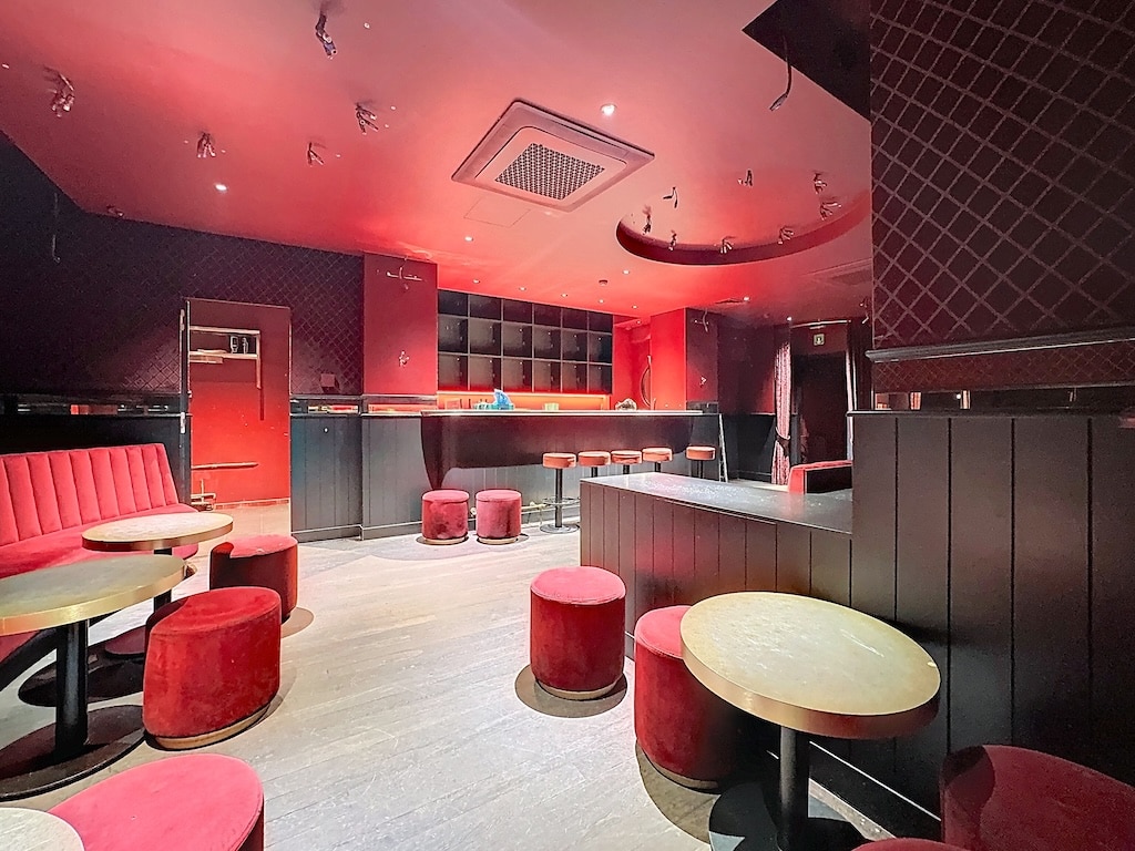 Bar lounge moderne à Uccle avec éclairage chaleureux et mobilier élégant.