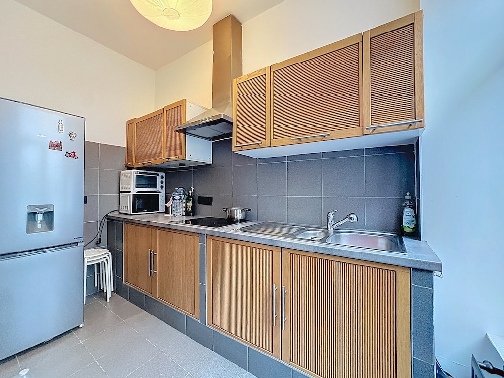 Cuisine moderne en bois avec backsplash bleu, électroménagers fonctionnels à Louvain.