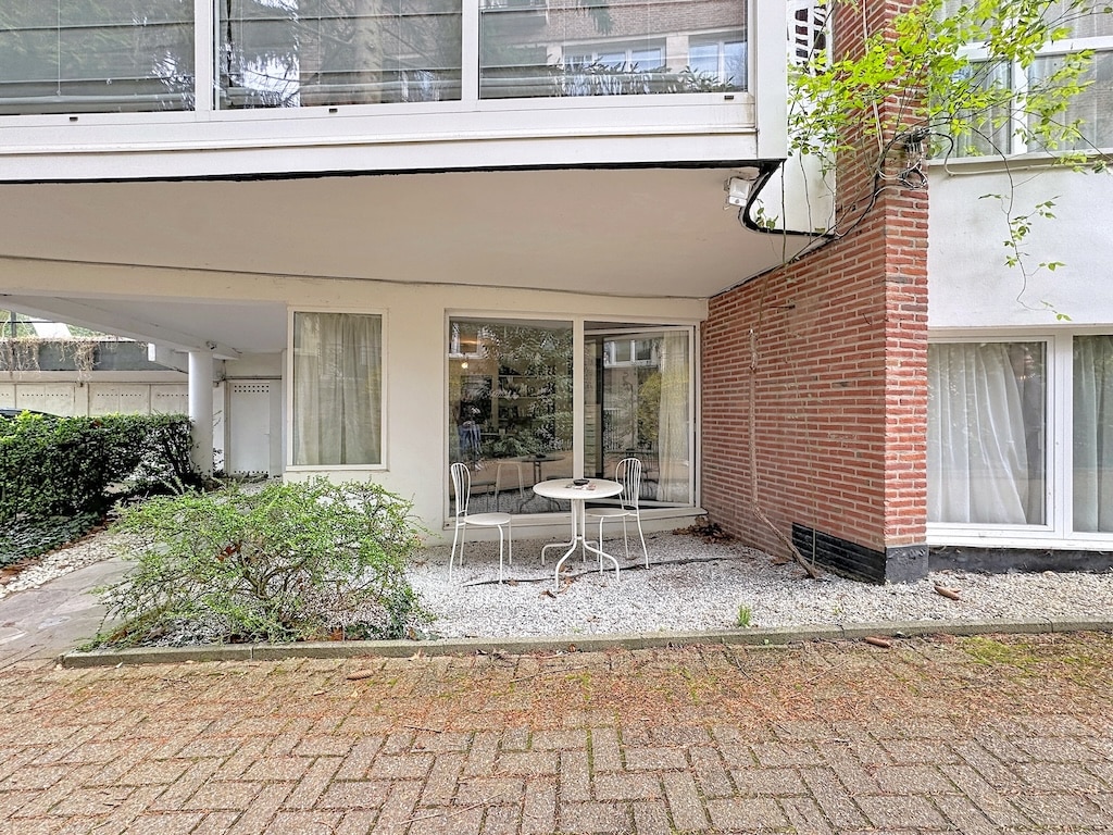 Eigentijdse gevel in Villeurbanne met rode baksteen, links geplaatste ramen, patio en aangelegde tuin.