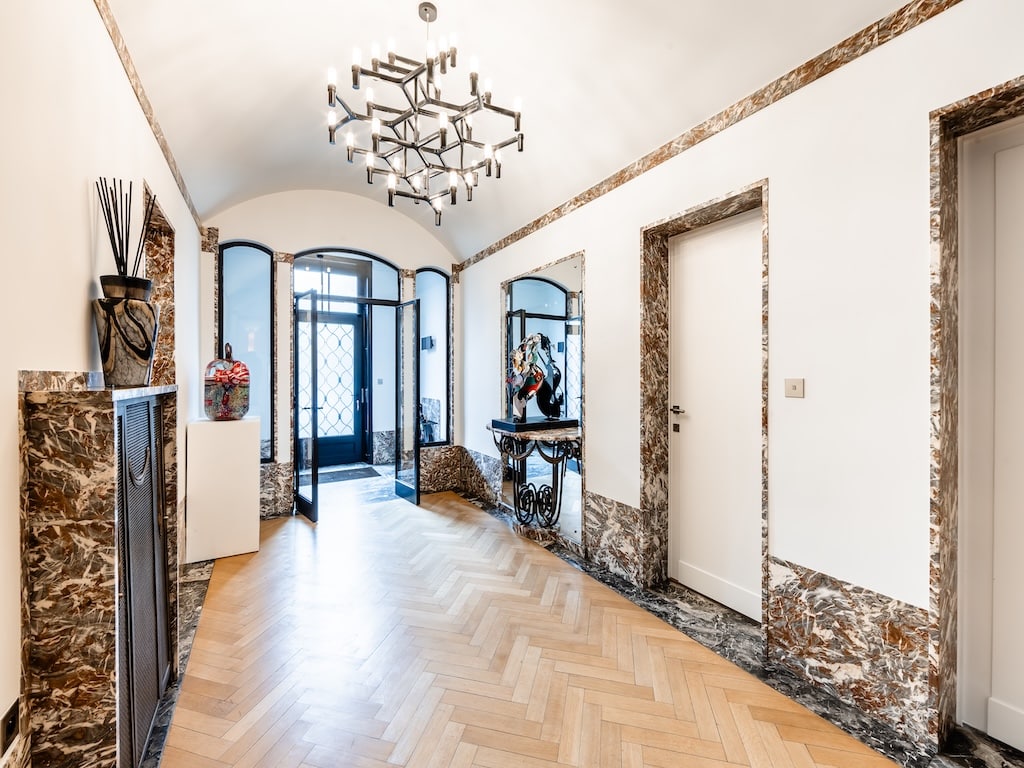 Hall dentrée élégant à Paris avec chandelier moderne, murs en marbre et portes en verre élégantes.