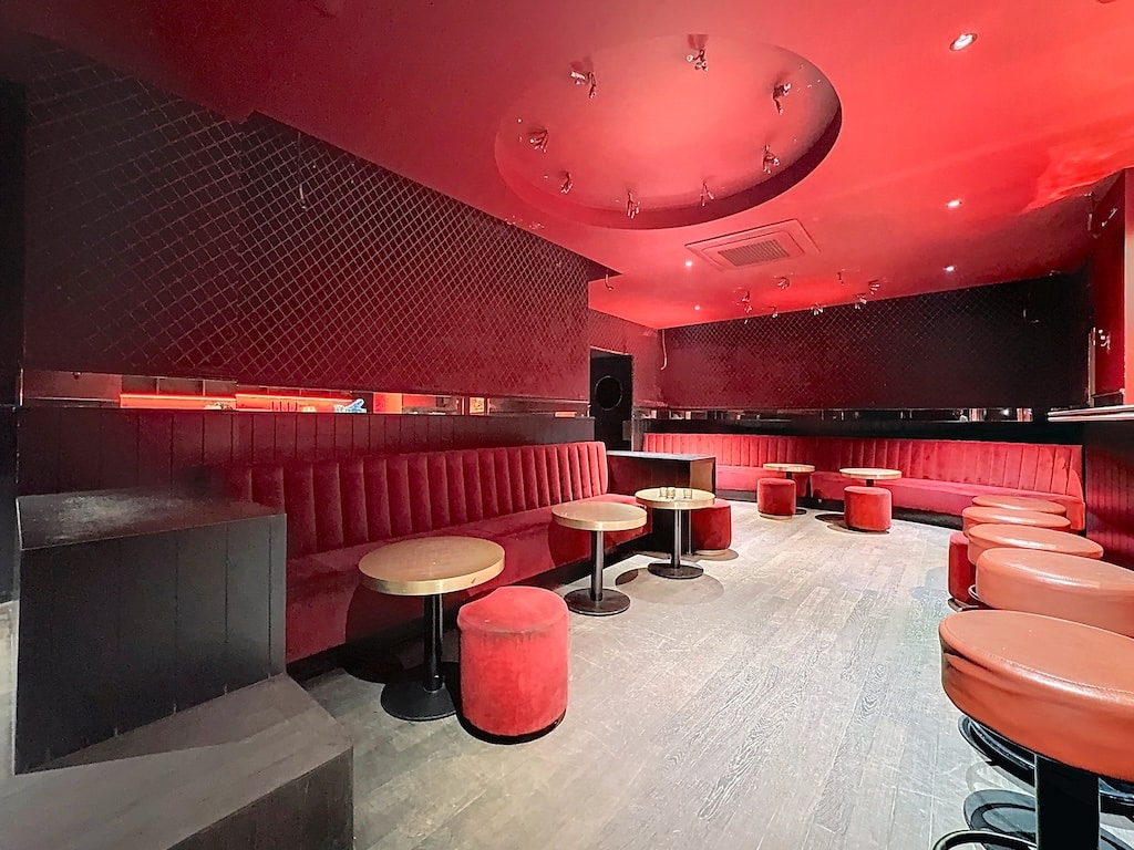 Lounge moderne et chic à Louvain, ambiance raffinée, mobilier rouge et éclairage chaleureux.